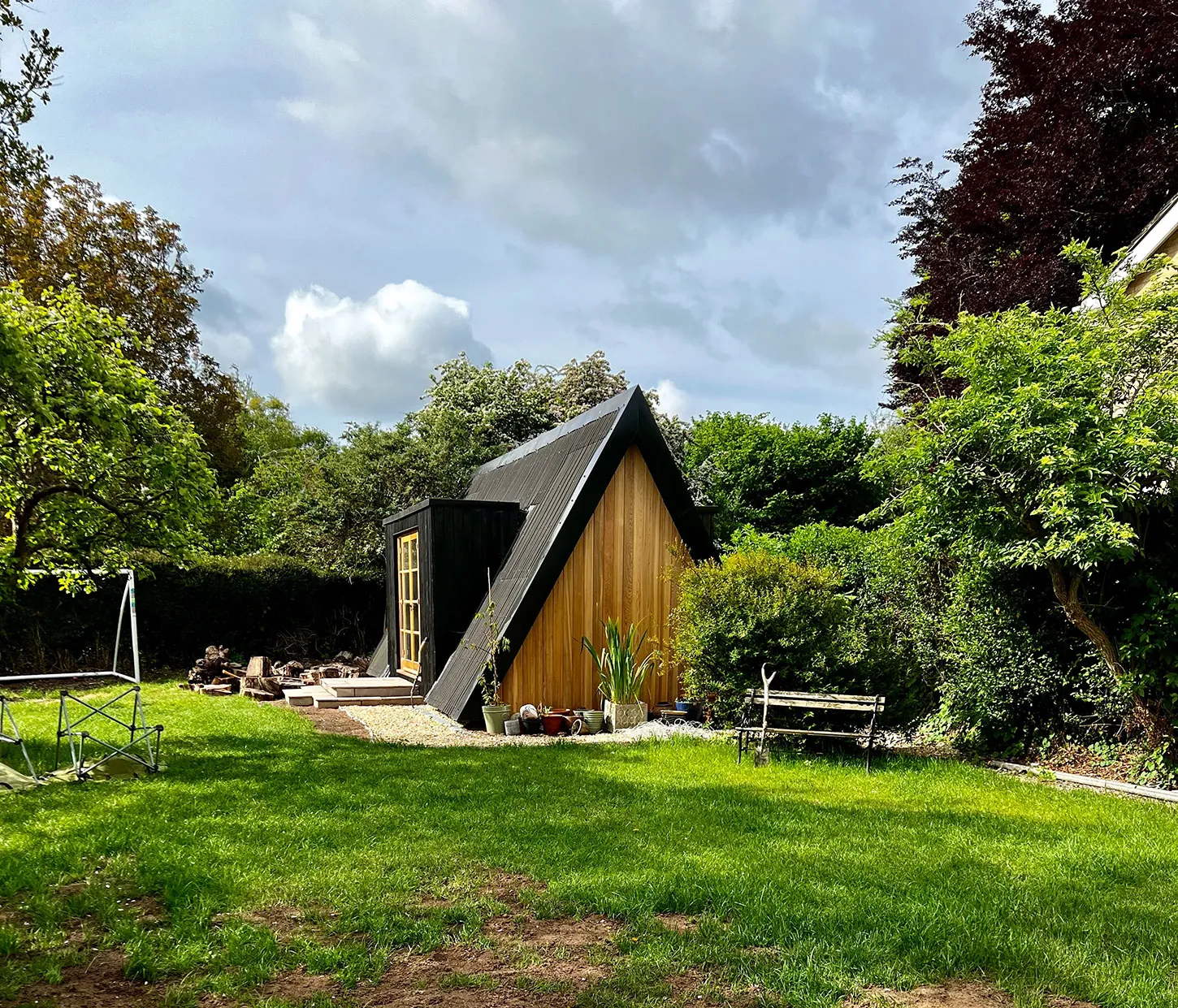 a small wooden building sitting in the middle of a lush green field